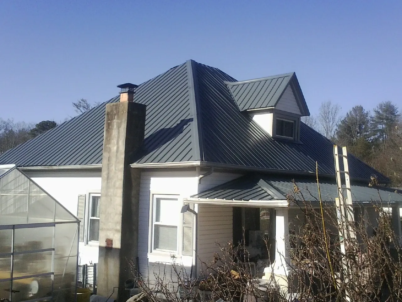 Dark blue standing seam metal roof on a white farmhouse with dormer — Slate & Tile Roof Repair by Roofing Brothers in Grove City