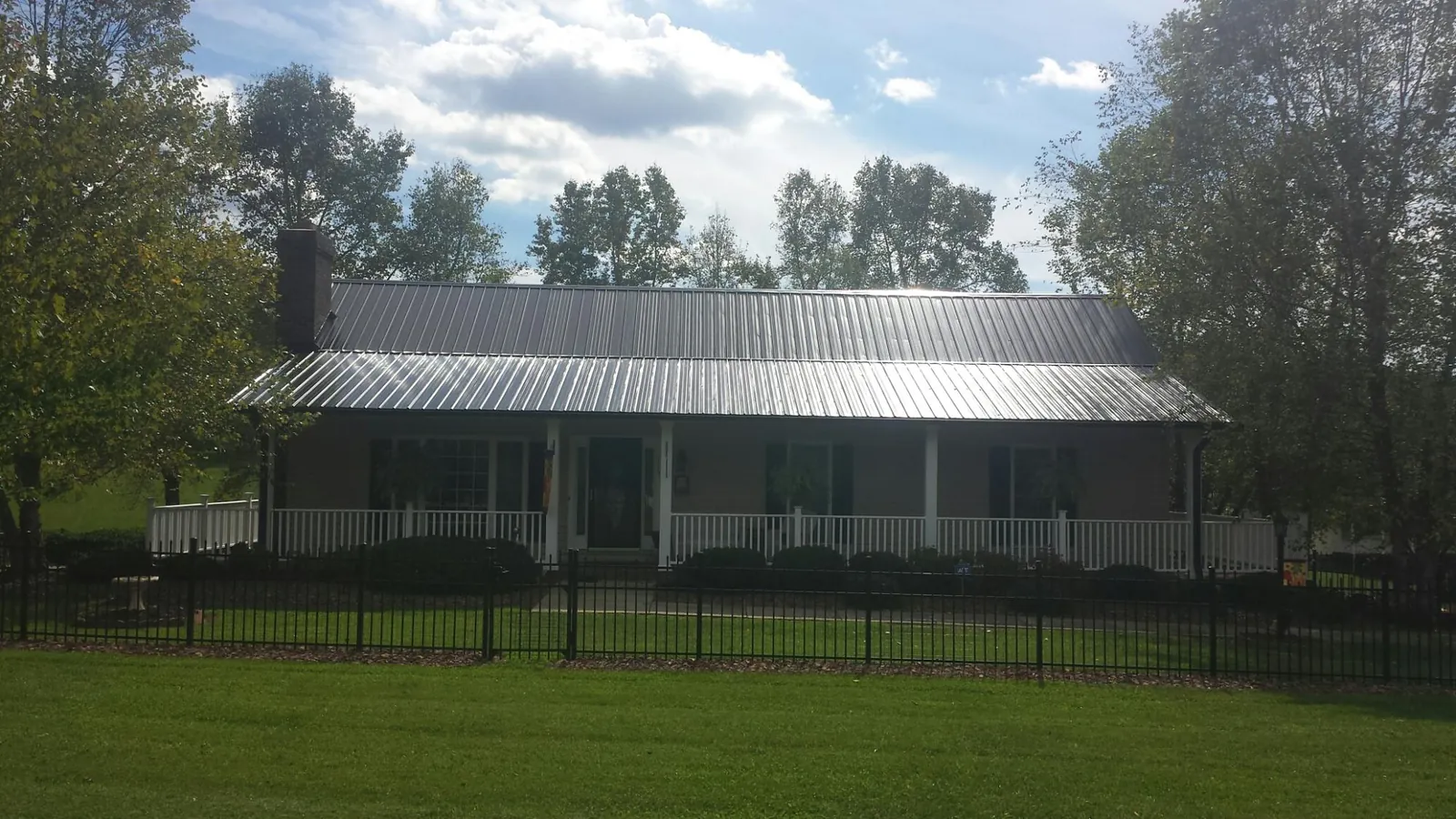 Gray metal roof on a brick ranch with a full width front porch — Gutter Guard Installation work by our crew in Grove City